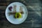 A small pistachio cake with a green coating and decorated with viburnum, confectionery dressing on a black background. Side view