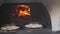 Small pizza baking in the oven burning fire. slow motion video. the cook prepares pastries lifestyle on an open fire