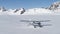 Small plane landing on snow in Alaskan mountains
