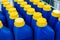 Small plastic canisters with chemical liquid. Blue bottles with a yellow cap at an industrial plant. No marking. Close-up