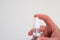 Small plastic hand sanitizer bottle with spray head held in hand by Caucasian male hand isolated close up shot