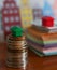 Small plastic house model on top of stacked coins