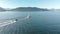 A small pleasure craft towing a dingy with Howe Sound and the mountains in the background on a sunny day. 24FPS 4K.