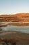 Small pond in a deserted area surrounded by hills under the sunlight and a blue sky