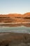 Small pond in a deserted area surrounded by hills under the sunlight and a blue sky