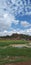 Small pond, green grass and garbage and man cars bike and blue sky and cloud