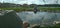 A small pond lined with stones with a view of the gazebos and the river