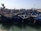 A small port in Africa, blue boats, seagulls flying, the sun shining.
