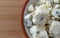 Small portion of crumbled blue cheese in a small bowl on a wood cutting board top close view