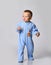 Small positive cute baby boy in blue warm comfortable jumpsuit standing and keeping balance