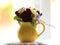 Small posy of spring flowers in a small, yellow jug on a windowsill.