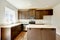 Small yet practical kitchen with brown cabinets and tile marble tops.