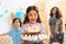 Small pretty girl with pendant chain on her head holds cake with candles at celebration of birthday.