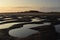 A small puddles in the sand after low tide in sunset light