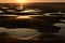 A small puddles in the sand after low tide in sunset light