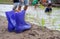 Small purple boots on the ground with blurry background of kids growing rice in the rice-filed