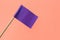 Small purple paper flag on pink background, closeup. Space for text