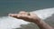 a small pyramid of colored stones in a man`s hand against the background of the sea surf.