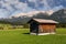 A small, quaint house nestled in a stunningly vibrant green meadow in Leutasch, Tyrol, Austria