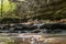 A small rapid river flows through dolomite rocks, long-term exposure, gentle and fuzzy river water, colorful autumn leaves and dry