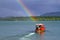 Small red boat on the river with rainbow