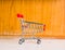 Small red cart on white table and wooden background. Cutest decoration.