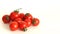 small red Cheri tomatoes with green tails lie scattered on a white background close up