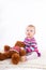 Small red hair baby girl playing with teddy bear on white background