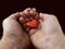 A small red heart in the palms of men. A man holds a tender heart in his hands. Love in male hands, on a black background. Concept