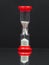 Small red hourglass with white sand and reflexion