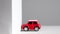 A small red model car crashes into a building wall. Crash test automotive vehicle wall.