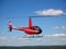 Small red rescue helicopter flying in blue sky