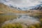 Small red tourists shelter house and mountains lake with snowy peaks of Swiss Alps reflection