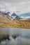 Small red tourists shelter house and mountains lake with snowy peaks of Swiss Alps reflection