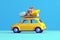 a small retro car packed with luggage and beach equipment on the roof, perfect for a summer road trip. The blue background and