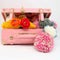 Small retro pink suitcase full of colorful woolen pom pom caps and scarfs