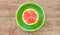 Small ripe halved watermelon on a green plate on a wooden tabletop