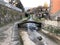 Small river with a bridge above it surrounded by houses and greenery in Borgo a Mozzano in Italy