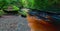 Small river with red water flowing through Finnich Glen landscape