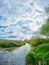 small river with scirpus, willow, grass and bushes on the banks