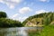 Small river in wild lands among hills overgrown by forest at sum