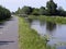 Small road along a canal with waterlilly`s and daughter flowers