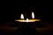 Small round candle burning in the dark table