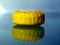 Small round hotel soap in yellow paper wrap on glass surface with reflections