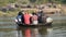 Small round riverboat loaded with people floating on the river.