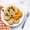 Small round waffles and fruits on grey background, flat lay