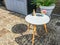 Small round white legged table with decorations on it in the backyard garden at home