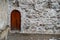 Small Rounded Wooden Medieval Middle Ages Door in Ancient Stone Wall on the Street with Copy Space