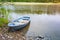 Small rowboat lays on coast of still lake