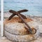 Small rusty anchor lying on a round stone